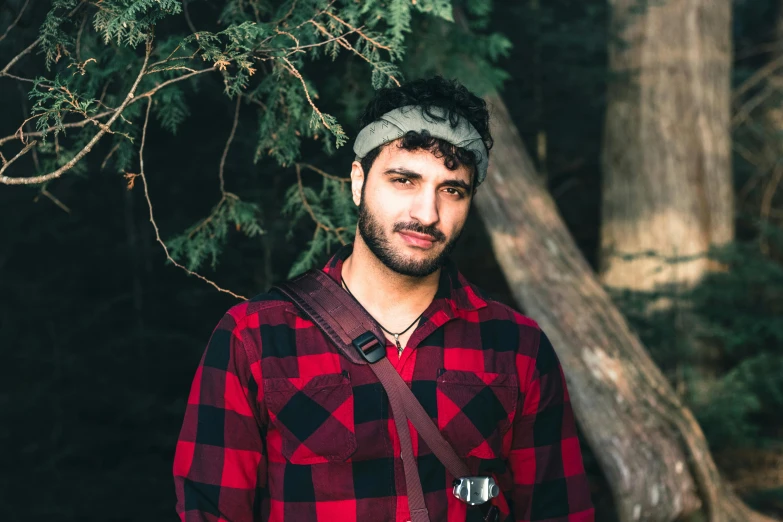 a man in red and black shirt standing in the forest