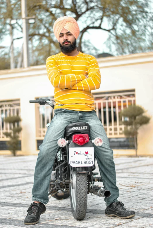 man sitting on motorcycle with hat and jeans