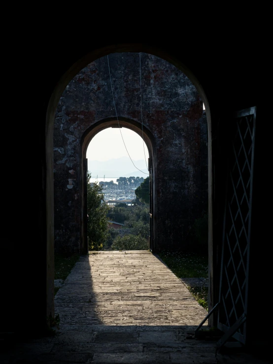 an arch entrance in the wall with a view to a park