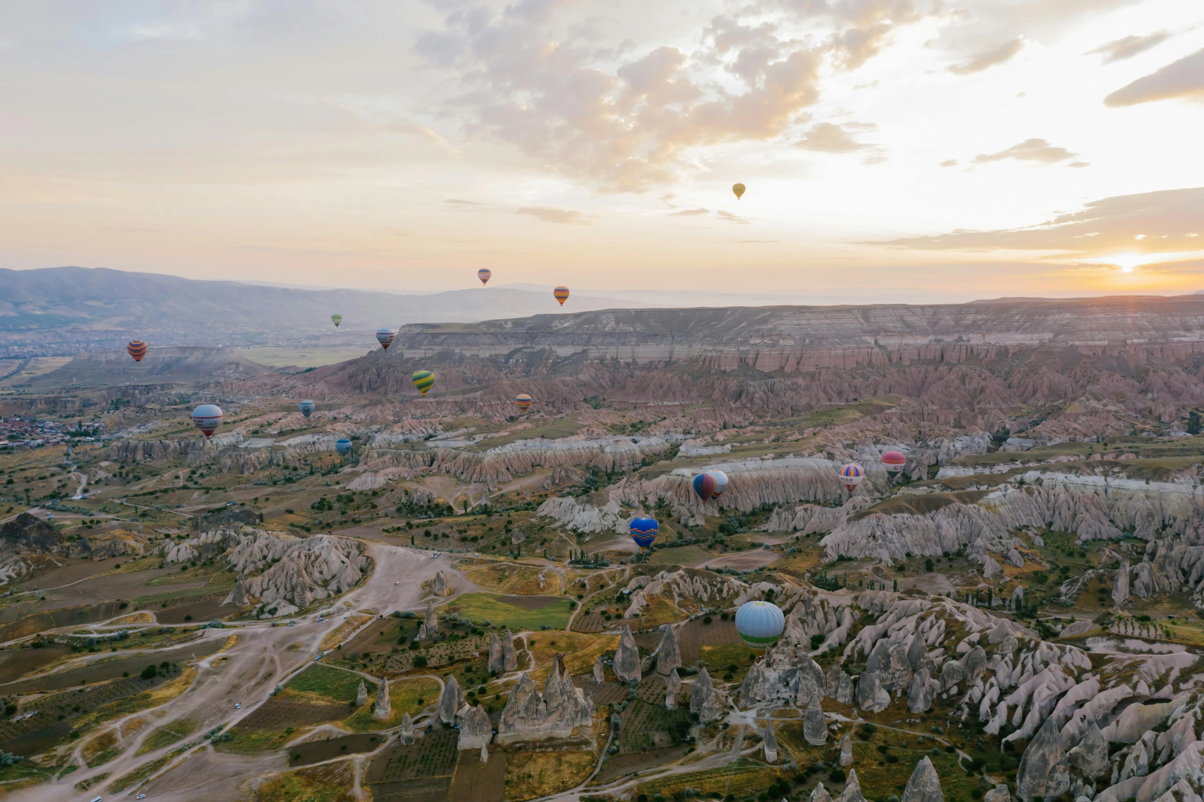 a landscape that has many balloons flying over