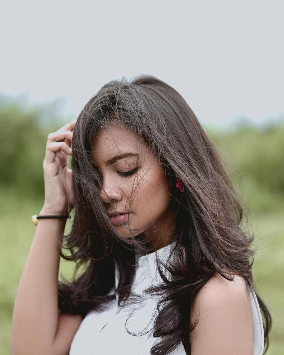 an attractive woman in a white dress stands looking down