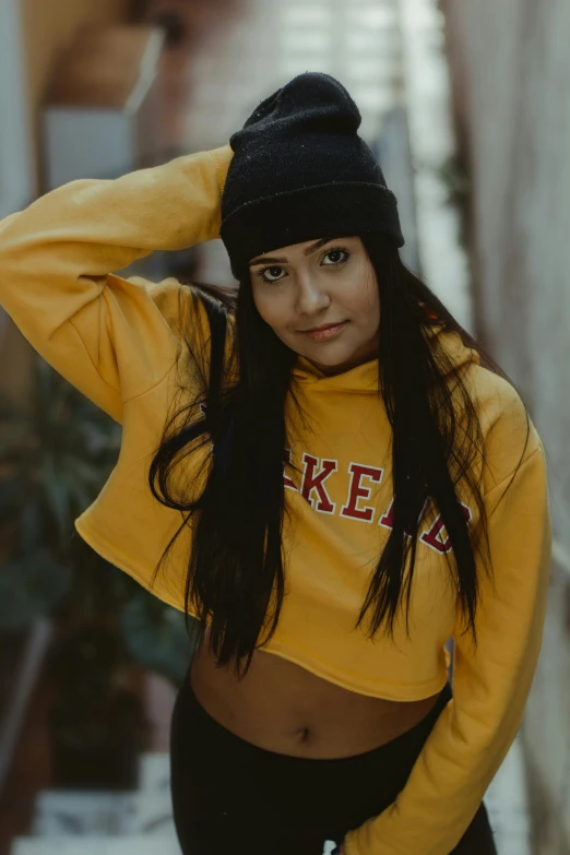 a girl is posing with her arms behind her head