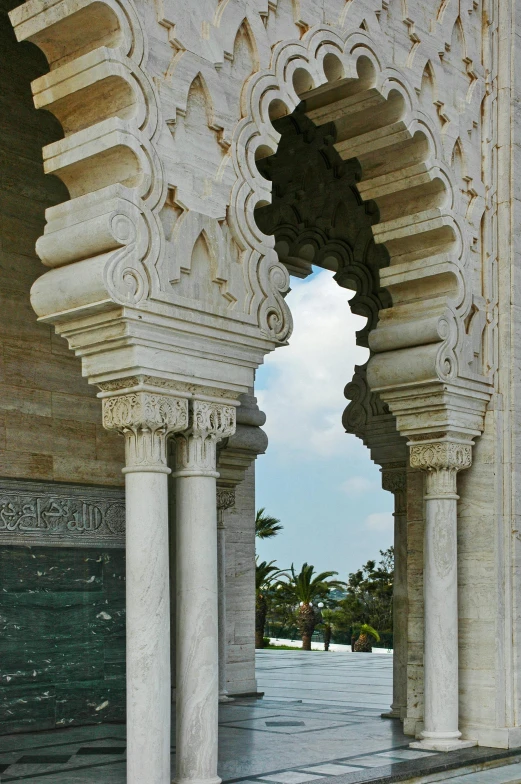 an archway between two white columns leading into a large pool