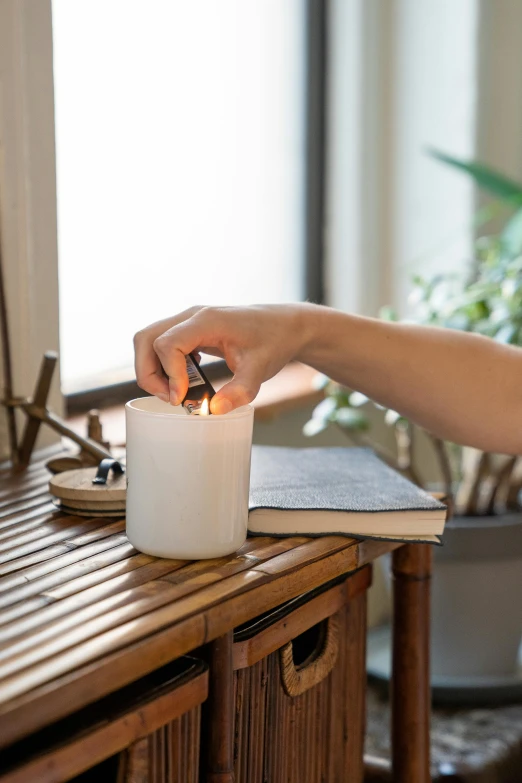 someone lighting a candle on a table