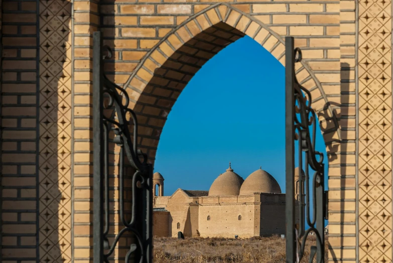 looking through an iron gate at two buildings with two towers