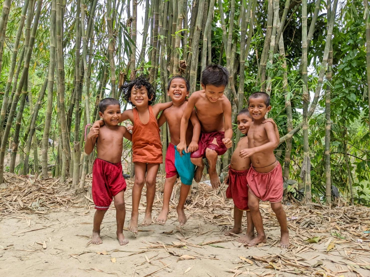 a group of young children posing in front of many bamboo trees