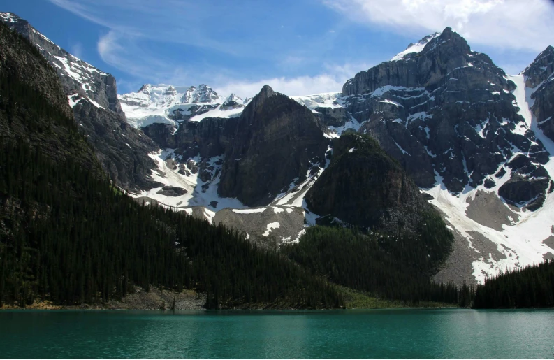 large snowy mountain covered in snow on the shore of a lake