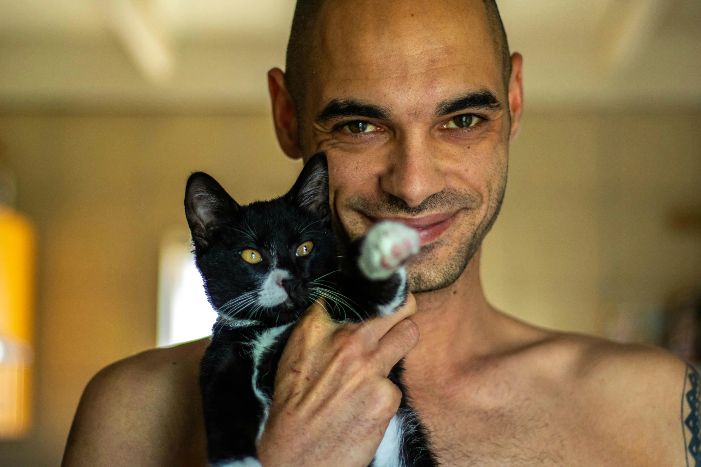 a man holding a cat while smiling for the camera