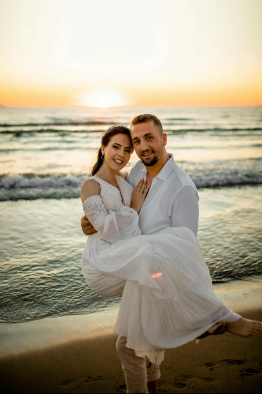 a couple standing on the beach at sunset