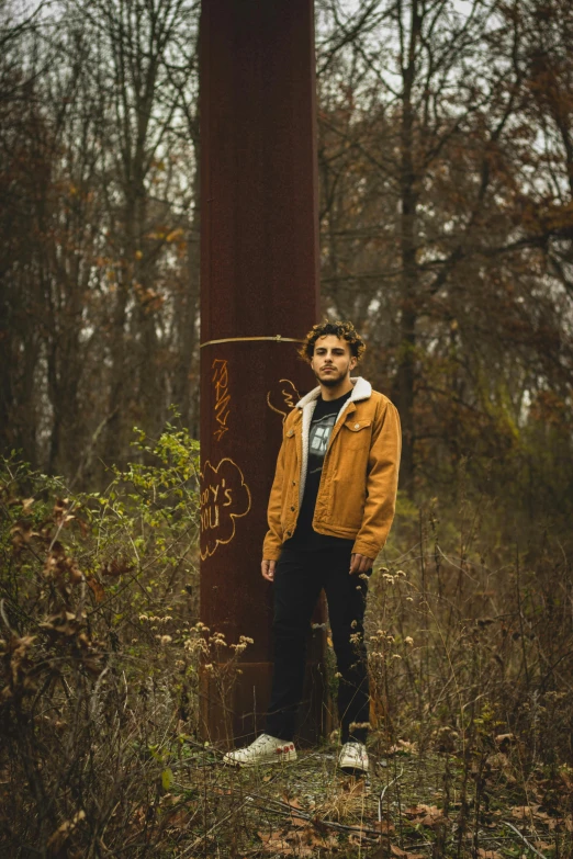 the man is standing beside a rusty pole