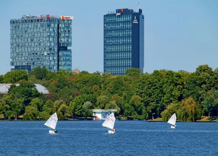 some very pretty sail boats in the water by a big building