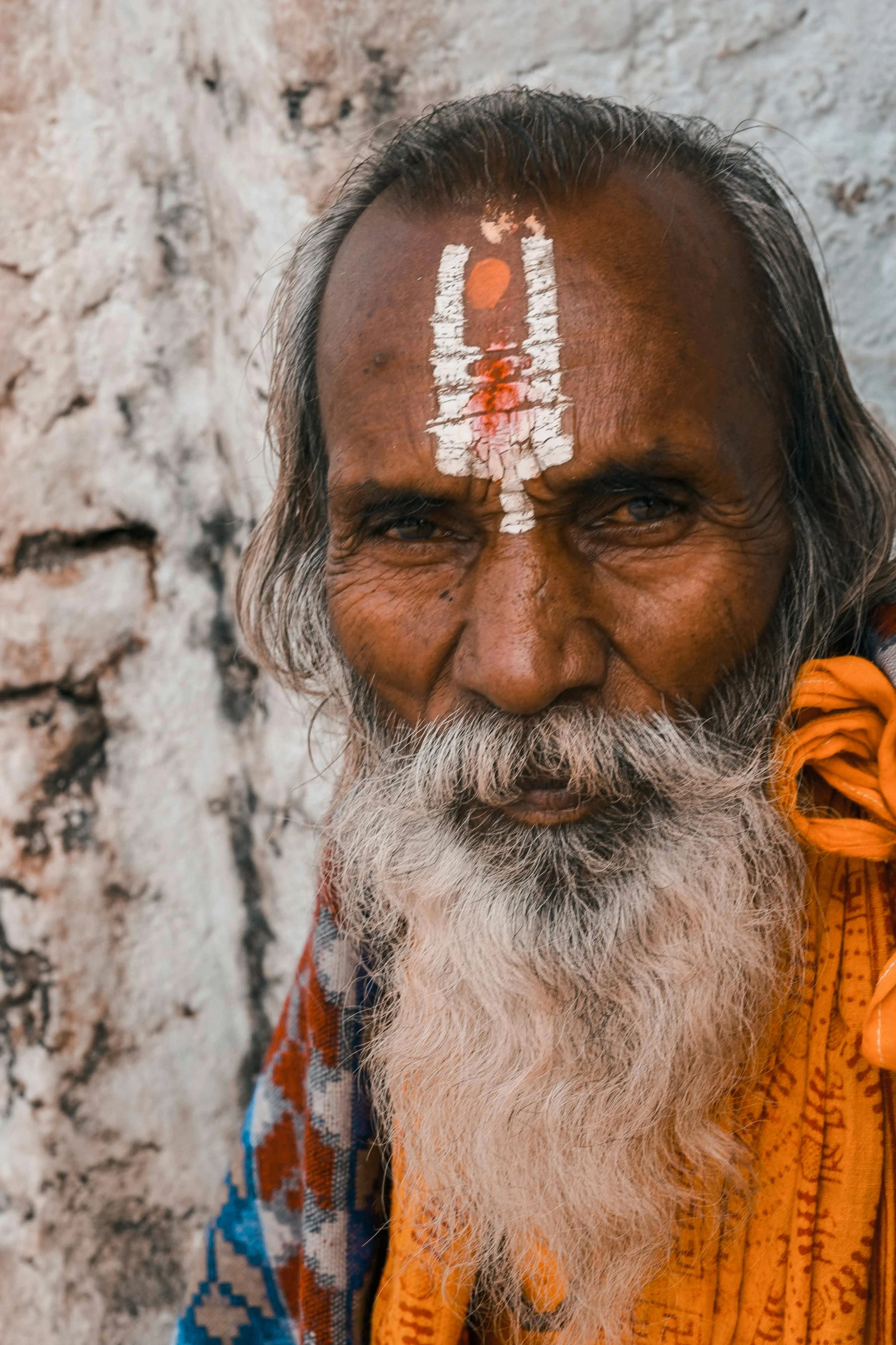 a man with a painted forehead sitting in front of a white building