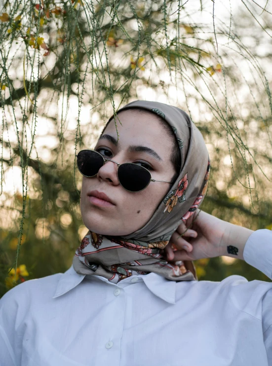 a woman standing next to flowers wearing sunglasses