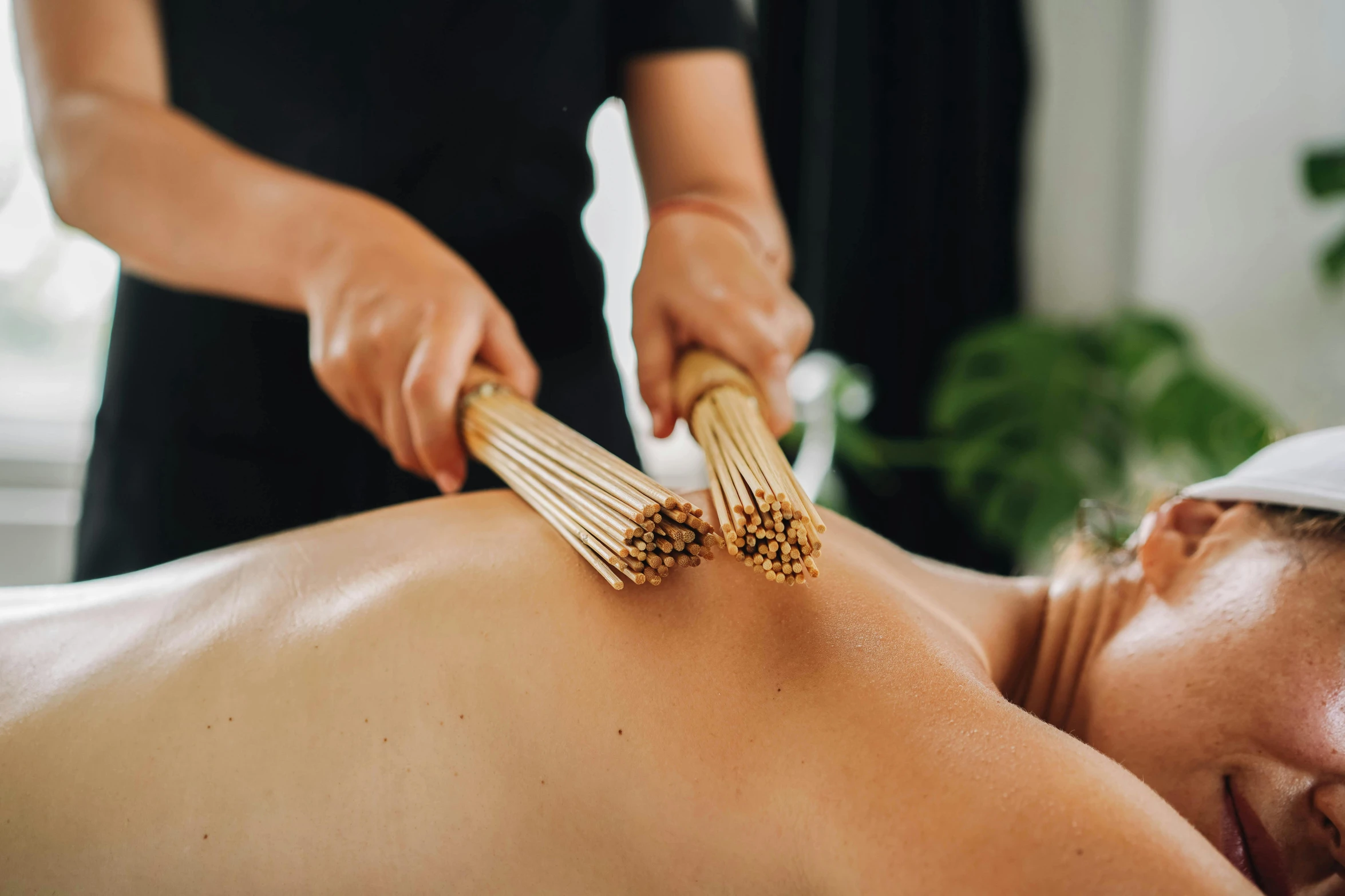 a woman having a back massage with a bamboo brush