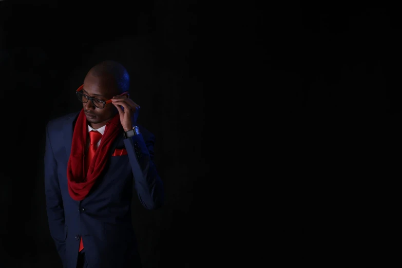 a man in a suit holding up his red scarf