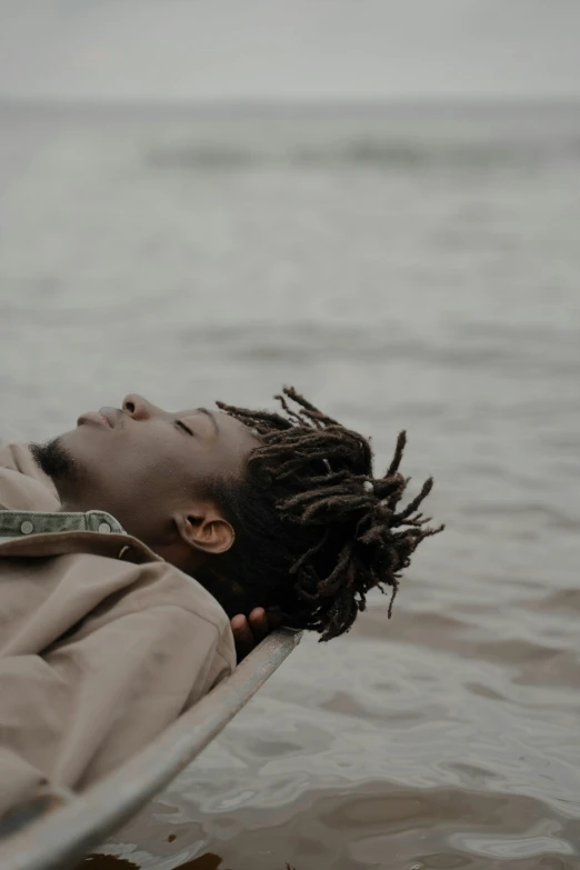 a man with dreadlocks floating in water with his head on the side