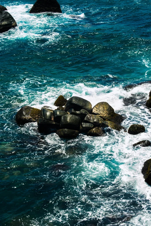 a couple of rocks sit next to the water