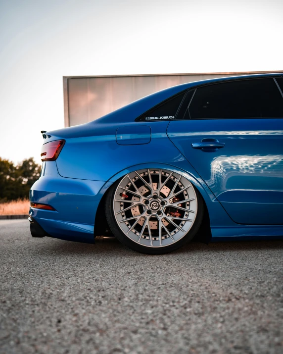 a blue car parked on a lot with one wheel missing