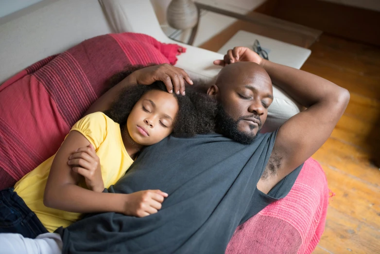 the adult and child are cuddled together on a couch