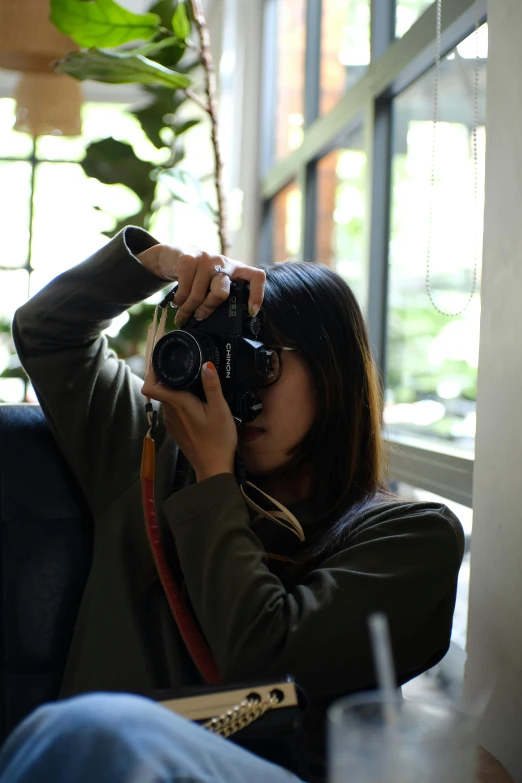 an asian woman taking pos with her camera