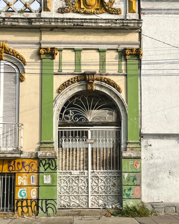 an ornate doorway and fence to a building with graffiti on the side of it