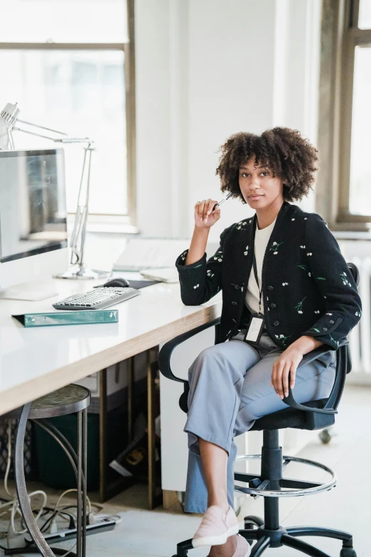 woman sitting in a chair at a desk with an office on one side and one side of the desk with a computer on top