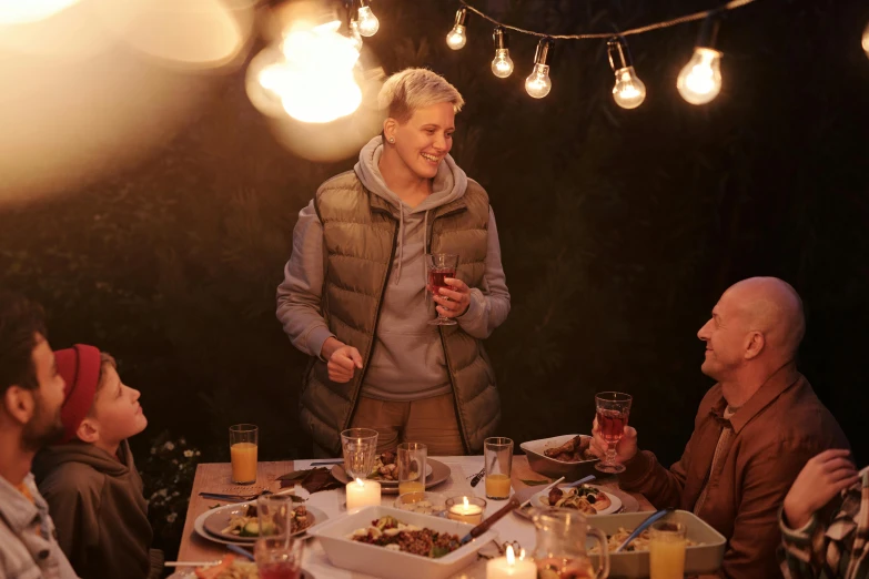 a man in a vest standing next to a table full of people