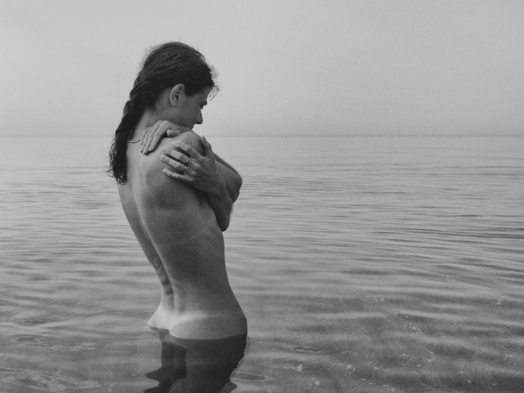 man in swim trunks holding woman over neck while in water