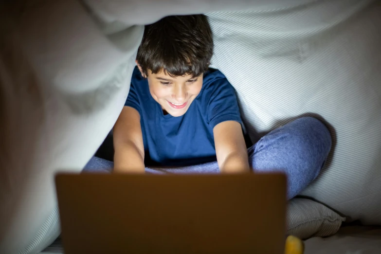 a boy playing on his laptop at night