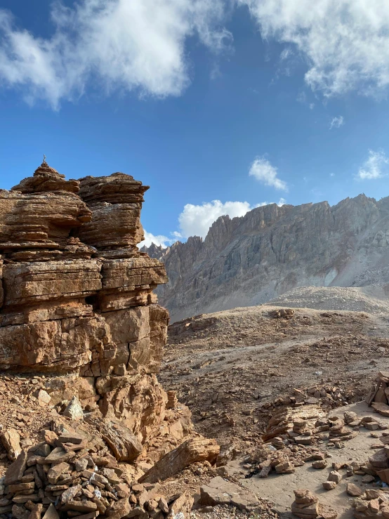 a rocky hillside under a blue sky with clouds