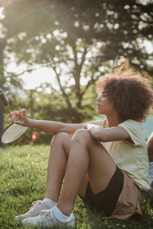 the woman in white is sitting on grass with her tennis racket in hand