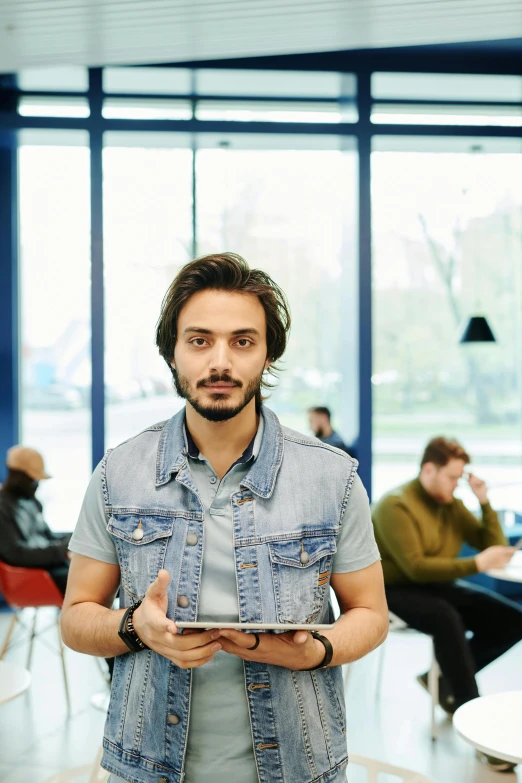 a man standing in front of some chairs while holding an electronic device