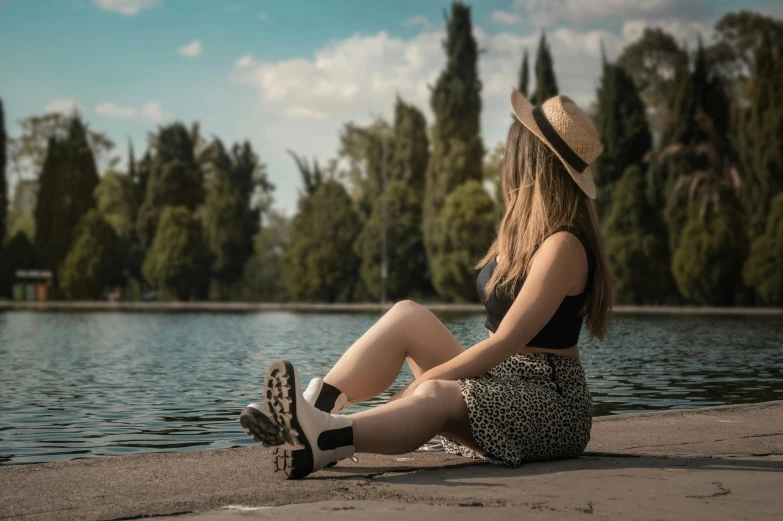 a girl sitting on the side of a lake