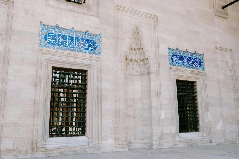 two windows with ornate decorations on them next to a wall