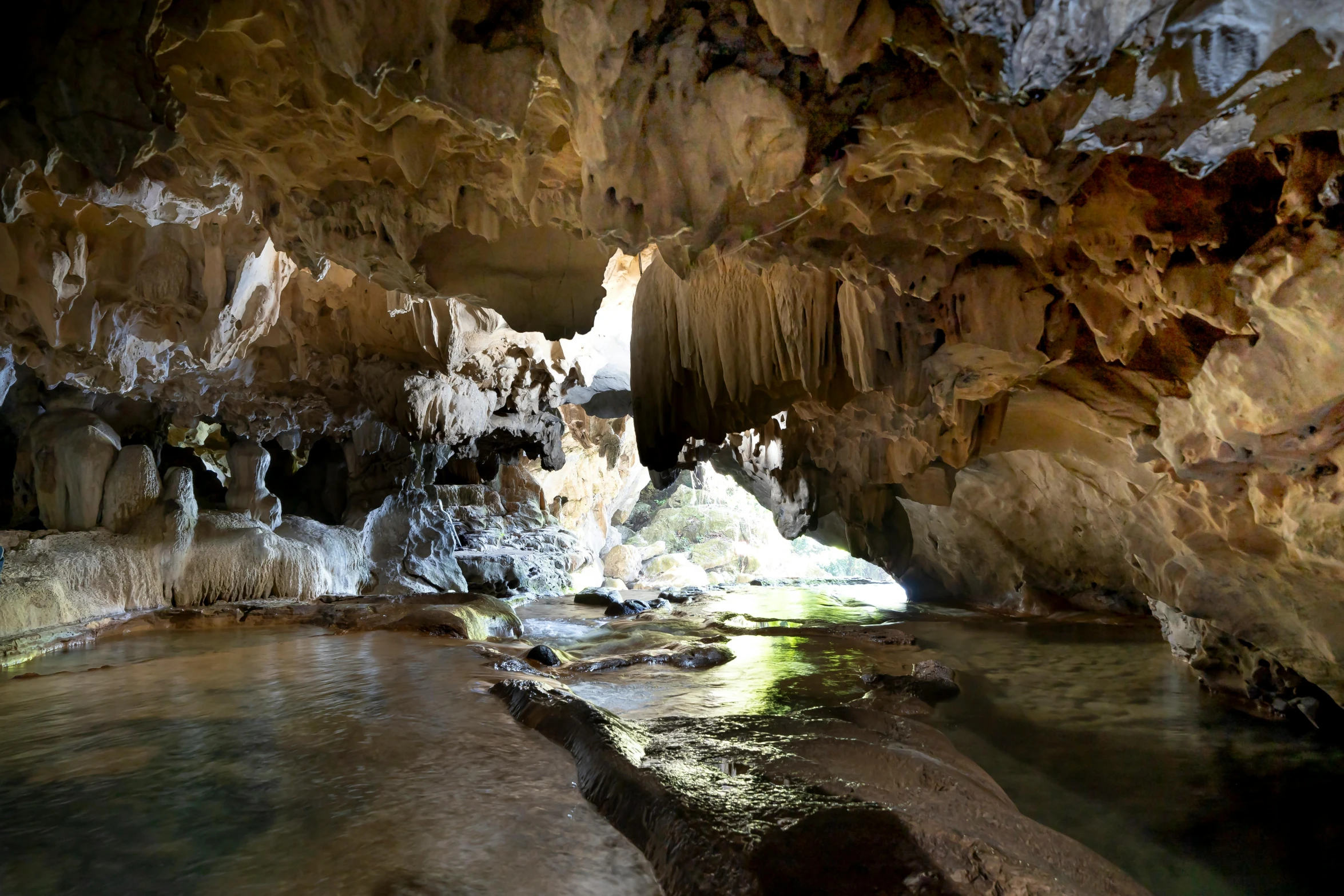 a river running through a cave next to the shore