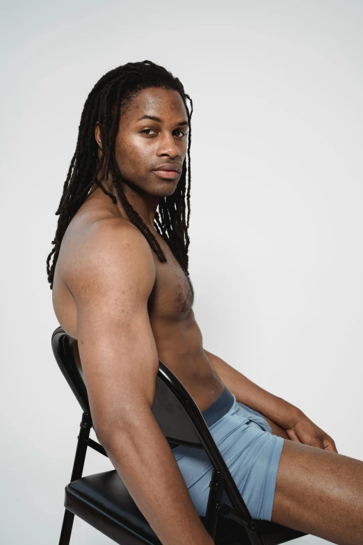 a shirtless black man sitting in a chair