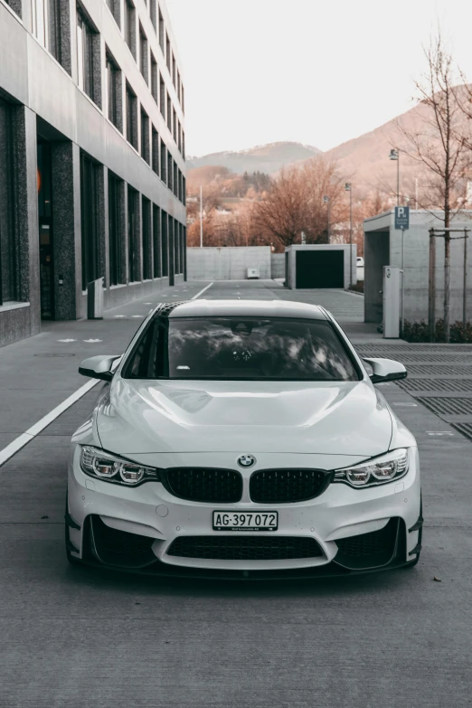 a white bmw in a parking space next to tall buildings