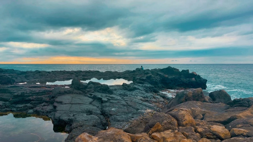 some rocks and water under a cloudy sky