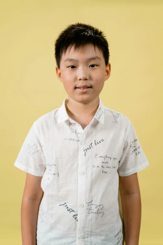 a small boy poses in front of a wall