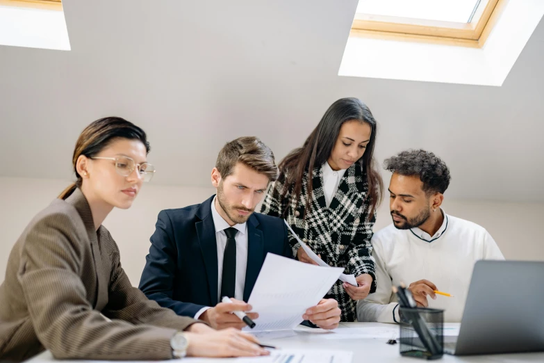 there are three men and a woman working on a piece of paper