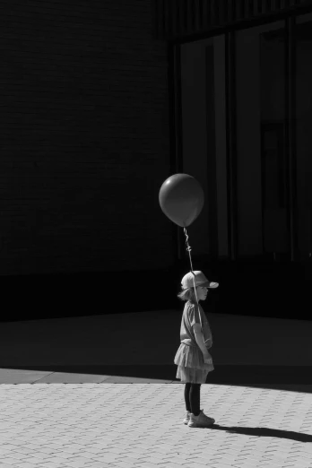 the little girl is holding on to a balloon while looking down