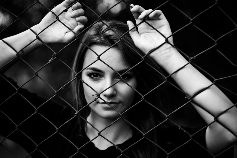 a woman is seen through a wire fence