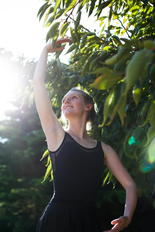 a woman wearing a black dress and holding her arm in the air as she is reaching for soing