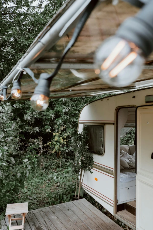 a camper in the woods has its door open and light on