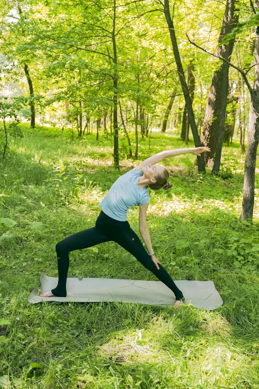 woman stretching on yoga mat in the woods