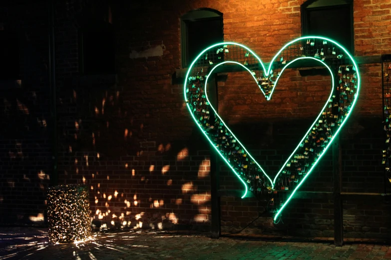 a heart - shaped neon sign made of christmas lights on a brick wall