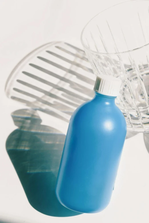 a blue bottle of some sort is next to a clear bowl