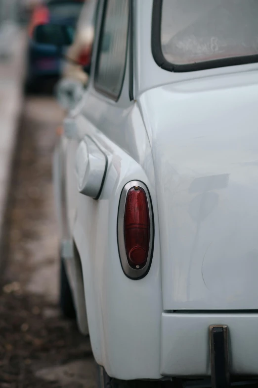 white older style car sitting on the side of a road