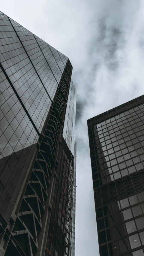 two very tall skyscrs rise high into the cloudy sky