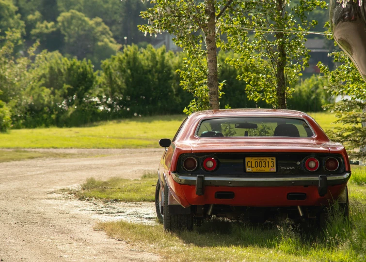 an old car is parked on the side of a dirt road